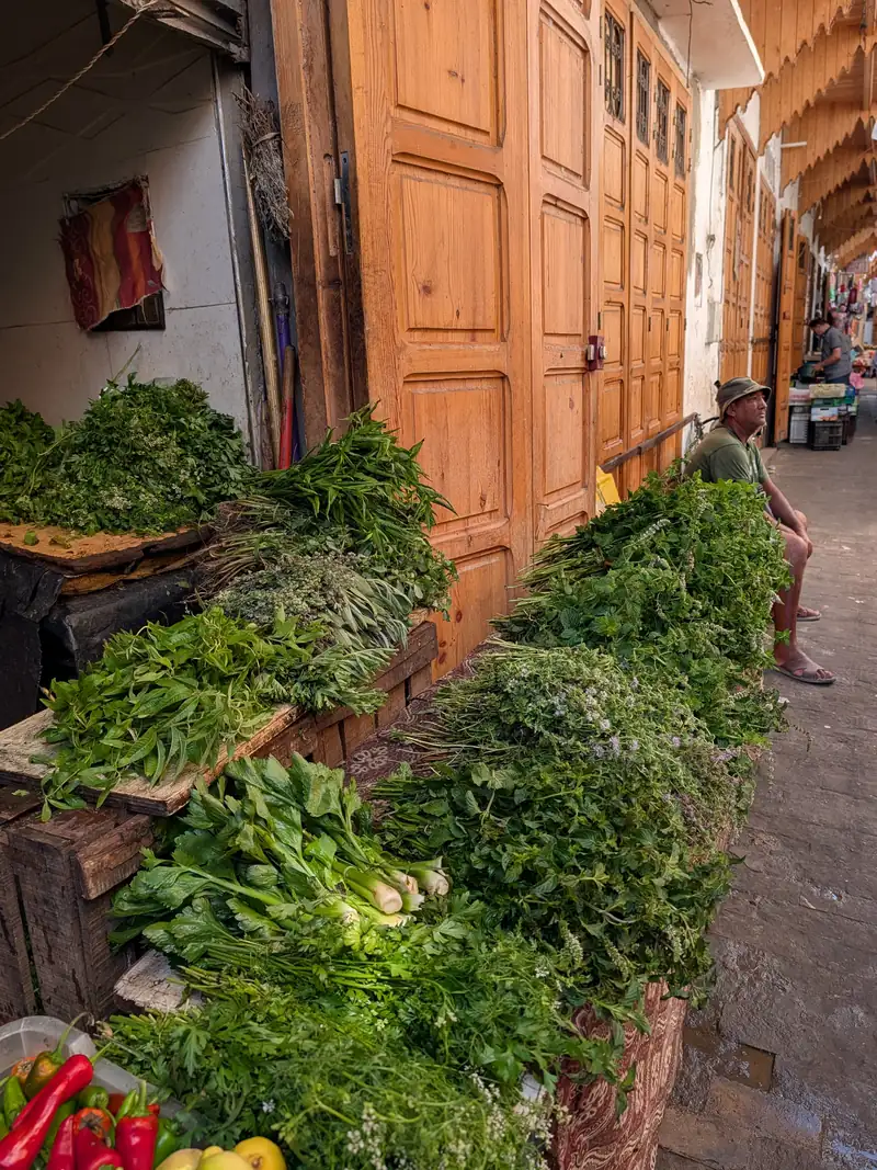 Étal d'herbes fraîches devant des portes de boutiques en bois
