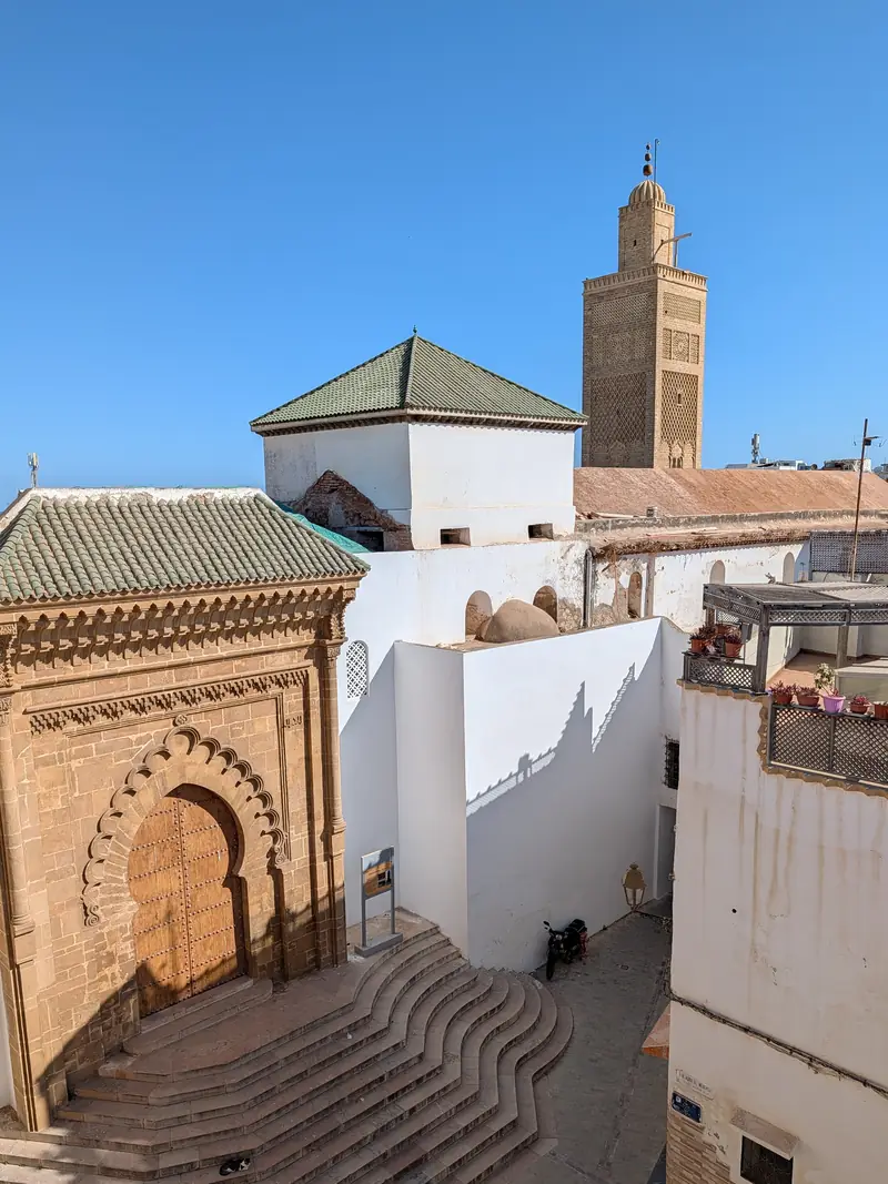 Le minaret de la Grande Mosquée de Salé au-dessus des toits, un portail sculpté au premier plan
