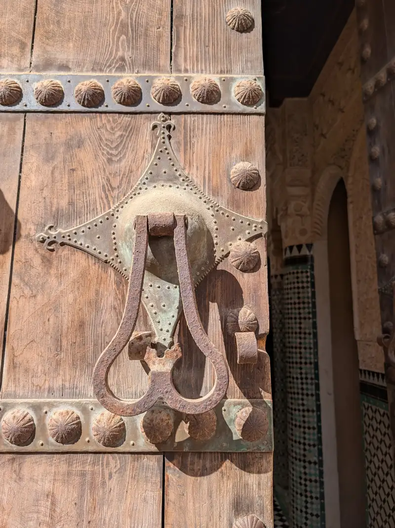Heurtoir en fer forgé sur la porte cloutée de la médersa