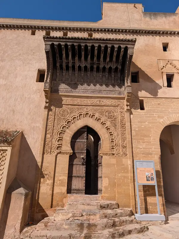 Porte de la médersa mérinide, encadrement de pierre sculptée sous un auvent de bois