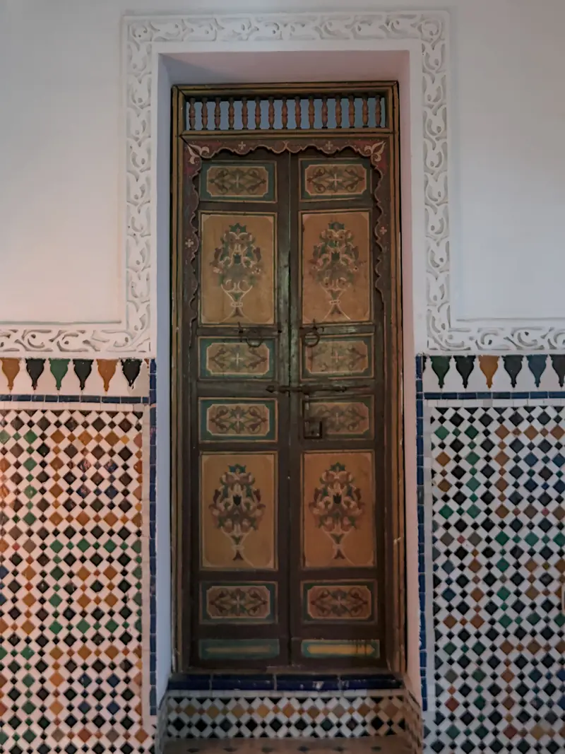 Porte à deux battants en bois peint, encadrée de plâtre sculpté et de zellige